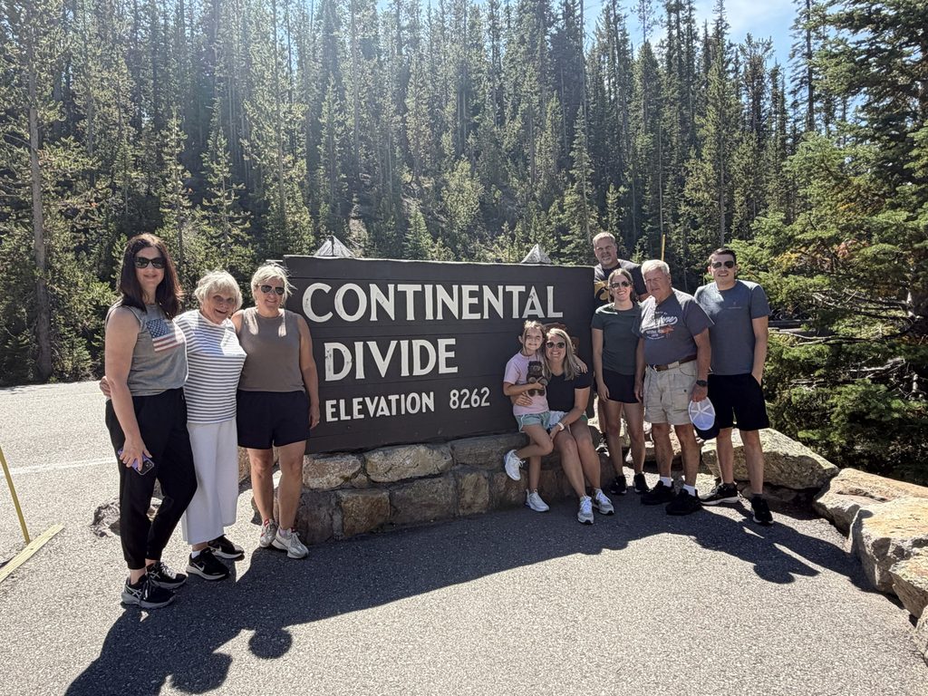 Family posing together at the Continental Divide sign during their Yellowstone trip.
